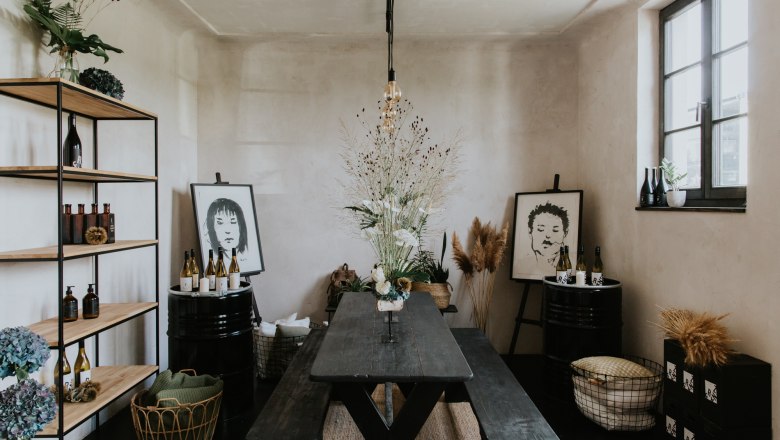 Franz von Grün, © Agentur Werbereich, Bianca Hochenauer Ein stilvoll eingerichteter Raum mit Holztisch, Regalen, Pflanzen und Kunstwerken an den Wänden.