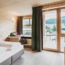 Gourmetrestaurant Gaumenkitzel, © Molzbachhof Modernes Hotelzimmer mit Holzwänden, großem Bett und Balkon mit Bergblick.