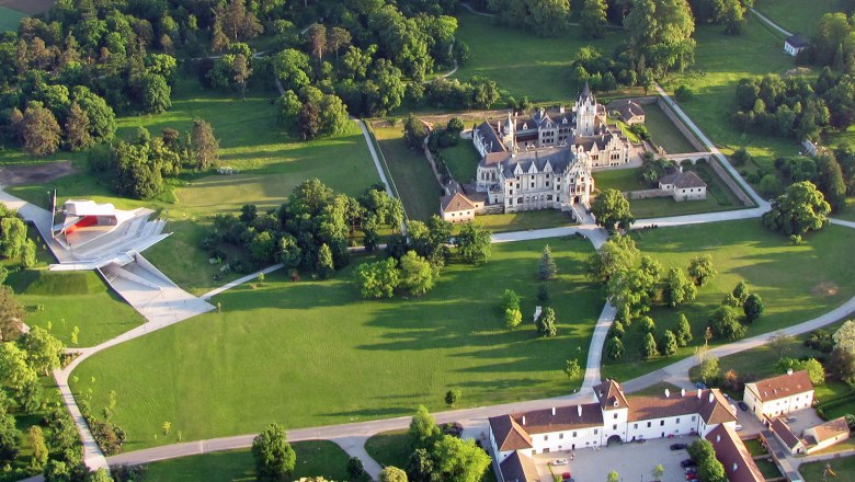Luftaufnahme, © Grafenegg Luftaufnahme von Schloss Grafenegg mit umliegendem Park und moderner Bühne.