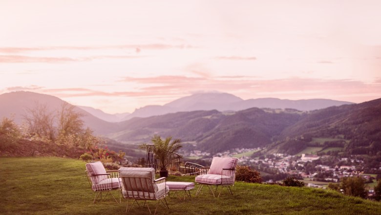 Aussicht vom Fernblick, © Matthias Kronfuss Sitzgruppe auf einer Wiese mit Bergblick bei Sonnenuntergang.