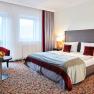 Doppelzimmer Hotel Schneeberghof, © Hotel Schneeberghof Doppelzimmer im Hotel Schneeberghof mit Doppelbett, roten Kissen, Tisch mit Obstschale und zwei Sesseln.