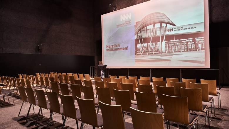 Museum Niederösterreich, Kino, © Klaus Engelmayer Leerer Kinosaal im Museum Niederösterreich mit Stuhlreihen und großer Leinwand.