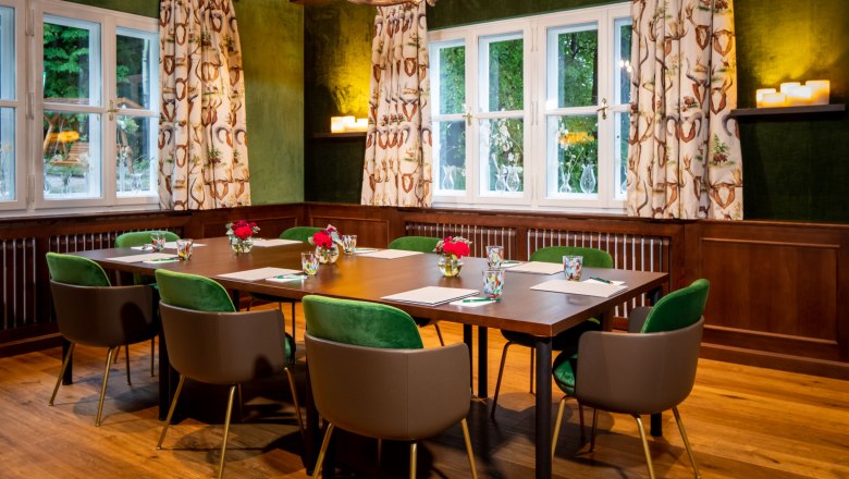 Knappenhof, Jagdzimmer, © Hotel Knappenhof, Christian Husar Ein Jagdzimmer mit Holztisch, grünen Stühlen und Geweihleuchter.