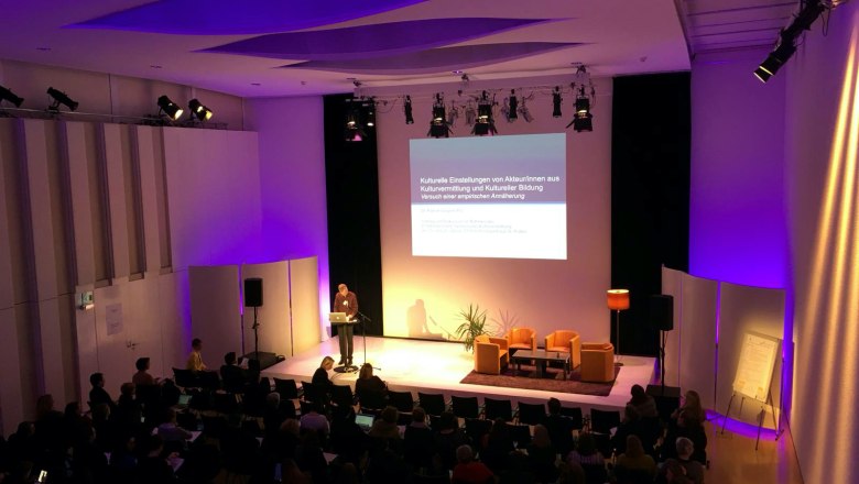 Festspielhaus St. Pölten, © Katharina Zettel Ein Vortrag in einem Konferenzraum mit lila Beleuchtung und Publikum.