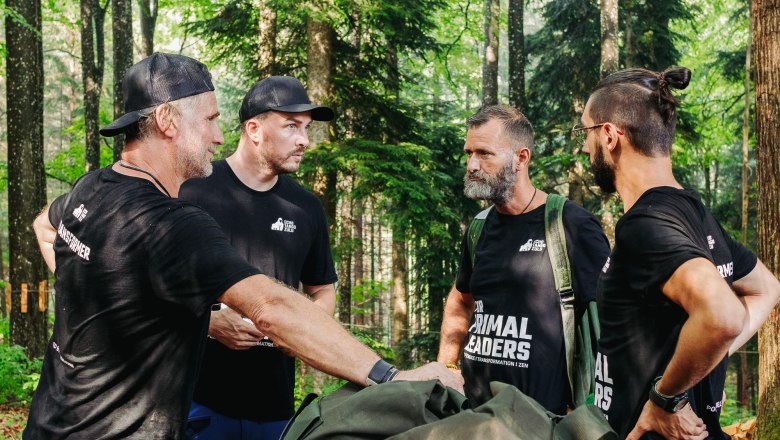 EchoTangoZulu, Primal Leaders, © EchoTangoZulu Vier Männer in schwarzen T-Shirts stehen im Wald und unterhalten sich.