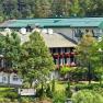 Der Schneeberghof in Puchberg, © Hotel Schneeberghof Ein großes Hotelgebäude mit grünen Dächern und Balkonen, umgeben von Bäumen und Natur.