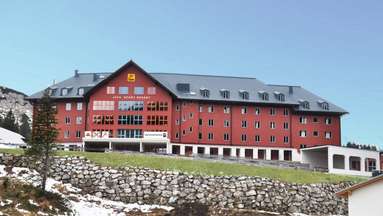Jufa Hochkar, © Jufa Hochkar Großes rotes Gebäude des Jufa Sport Resorts in einer bergigen Landschaft.