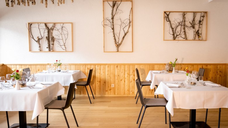 Parkhotel Hirschwang, Restaurant Raxblick, © Friedl und Schmatz Elegantes Restaurant mit Holzwänden, weißen Tischdecken und Birkenkunst an den Wänden.