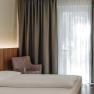 Comfort HEINhotel vienna airport, © HEINhotel vienna airport Modernes Hotelzimmer mit Bett, Sessel und Vorhängen.