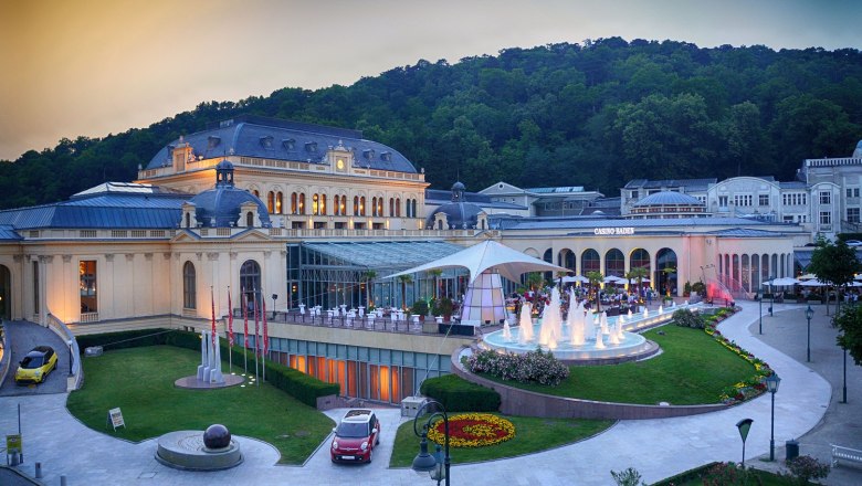 Congress Center Baden, © Casino Baden Außenansicht des Congress Centers Baden mit beleuchtetem Springbrunnen und umliegender Natur.