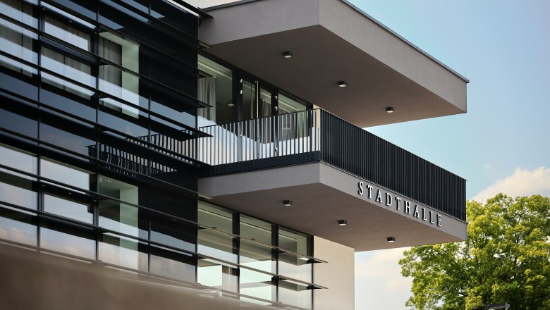 Aussenansicht Stadthalle Ybbs, © Johann Perger Moderne Außenansicht der Stadthalle Ybbs mit Glasfassade und Balkon.