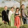 Gastgeberfamilie Pichler, © Rita Newman Familie Pichler in traditioneller Kleidung stehen im Freien vor einem Baum, im Hintergrund ist Sift Melk zu sehen