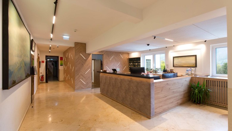 Flackl-Wirt - Rezeption, © Flackl - Wirt GmbH & Co KG Rezeption eines Hotels mit modernem Design, Holzelementen und einem großen Empfangstresen.
