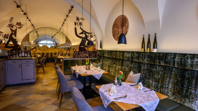 Restaurant im Hotel Zur Post, © Helmut Lackinger Elegantes Restaurant mit gedeckten Tischen, dekorativen Elementen und Weinflaschen auf einem Regal.