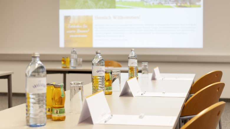 Parkhotel Hirschwang, Seminarraum, © Friedl und Schmatz Seminarraum mit Tischen, Stühlen, Wasserflaschen und Notizblöcken.