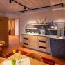 Aufenthaltsraum im Hotel-Spa, © Lachlan Blair / Loxpix Ein gemütlicher Aufenthaltsraum in einem Hotel-Spa mit Holzmöbeln, einer kleinen Küchenzeile und dekorativen Blumen.