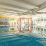 Hallenbad, © Hotel Schneeberghof Ein helles Hallenbad mit Liegestühlen und einem Wasserstrahl im Pool.