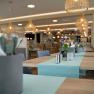 cafe-3, © Simon Kuntner Innenansicht eines modernen Cafés mit Holztischen, blauen Tischläufern und hängenden Lampen.