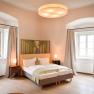 Freigut Thallern, © Freigut Thallern Ein elegantes Schlafzimmer mit Doppelbett, zwei Fenstern mit Vorhängen und stilvoller Beleuchtung.