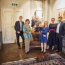Familie Pichler, © Familie Pichler Eine Gruppe von Menschen posiert in einem eleganten Raum mit einem Hund im Vordergrund.