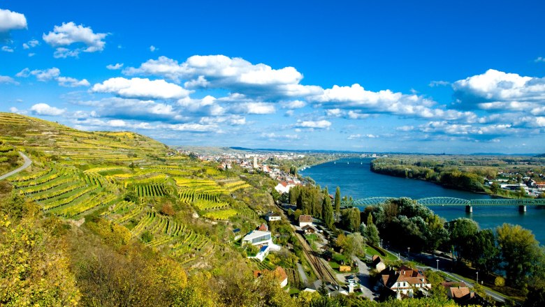 Convention Partner Krems, © ARGE Weinstrasse Kremstal, Robert Herbst Landschaft mit Weinbergen, Fluss und Brücke in Krems, Österreich.