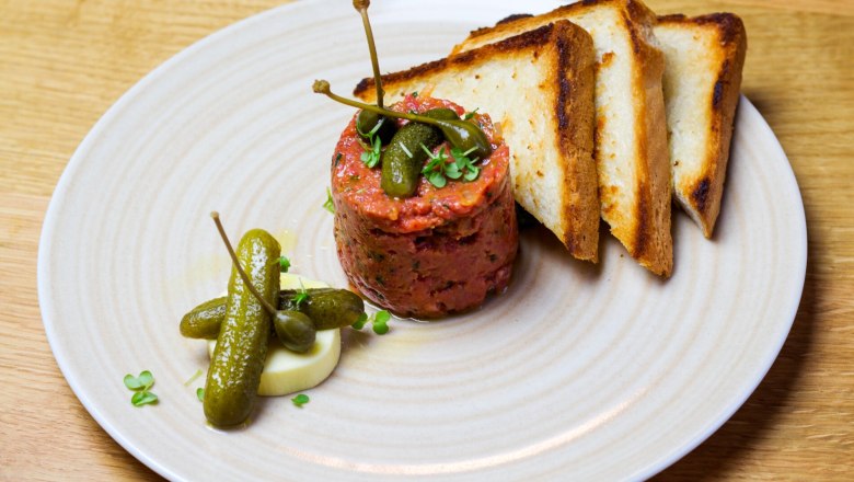 Beef tartar-angerichtet, © Weingut Nigl Beef Tartar mit Kapern, Gewürzgurken und Toast auf einem Teller.