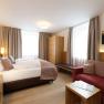 Zimmer im Hotel Donauhof, © Marcella Wallner Modernes Hotelzimmer mit Doppelbett, Sofa, Schrank und Fernseher.
