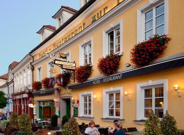 Fassade vom Hotel-Restaurant Zur Post, © Hotel-Restaurant zur Post Fassade eines gelben Gebäudes mit dem Schriftzug 'Hotel-Restaurant zur Post'. Vor dem Gebäude sitzen Menschen an Tischen.