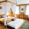 Gemütliches Hotelzimmer mit Himmelbett, Holzmöbeln und Teppichen.