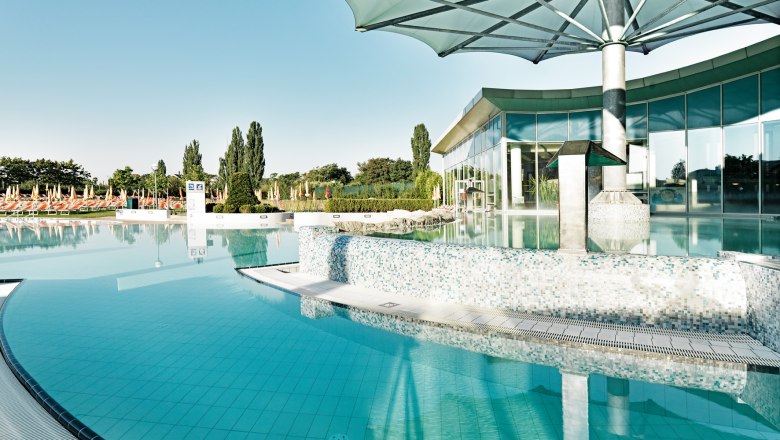 Au&szlig;enbereich der Therme Laa mit Pool und Sonnenschirmen.