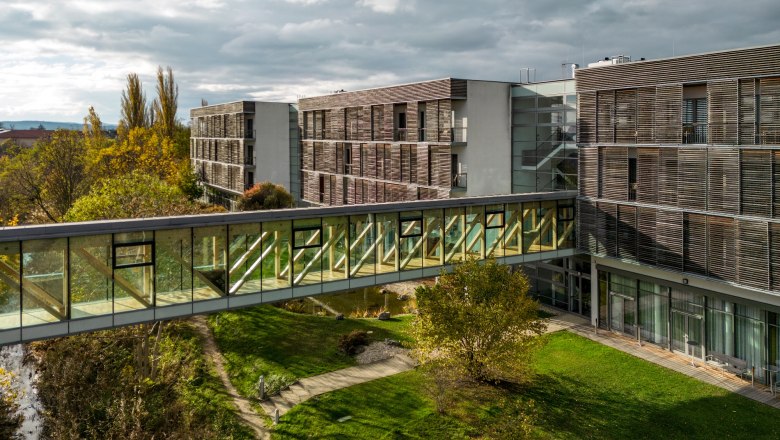 Moderne Hotelgebäude mit Glasbrücke und Garten.