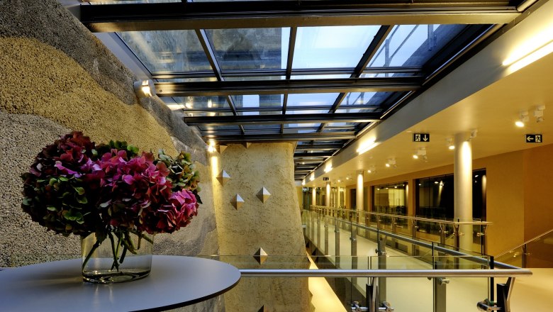 Modernes Vestib&uuml;l der Burg Perchtoldsdorf mit Glasdach und Blumenarrangement.