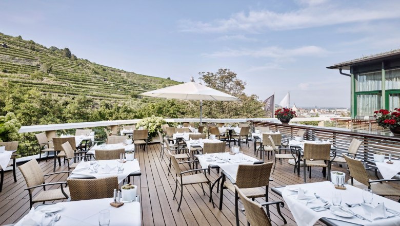 Restaurantterrasse mit gedeckten Tischen und Blick auf die Weinberge.
