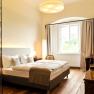Elegantes Hotelzimmer mit Doppelbett, Holzboden und gro&szlig;em Fenster.