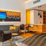 Moderne Hotelsuite mit Sofa, Sessel, TV und K&uuml;chenzeile.
