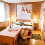 Gemütliches Doppelzimmer mit Holzmöbeln, einem Tisch mit Getränken und Snacks, und einem Bett mit Baldachin.