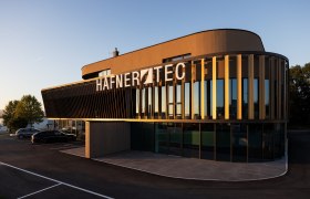Modernes Geb&auml;ude mit der Aufschrift 'HAFNER TEC' bei Sonnenuntergang.