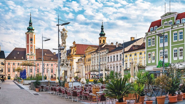 Rathausplatz in St. Pölten mit historischen Gebäuden und Außensitzbereich.