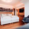Modernes Hotelzimmer mit Doppelbett, Holzboden und Wanddekoration.