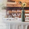 Eleganter Restauranttisch mit Gl&auml;sern und Blume in Vase.