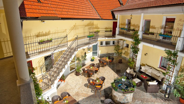 Innenhof der Residenz Wachau mit Tischen, St&uuml;hlen und einem Brunnen.