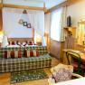 Gemütliches Hotelzimmer mit Doppelbett, Sofa, Schreibtisch und Spiegel in rustikalem Stil.