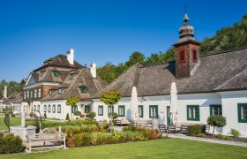 Schloss Luberegg mit gepflegtem Garten und blauen Himmel.