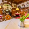 Gem&uuml;tliches Gastzimmer mit Holzm&ouml;beln, Tischdecken und Blumenvasen.