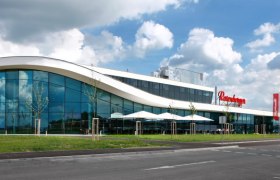 Modernes Gebäude mit Glasfassade und geschwungenem Dach.