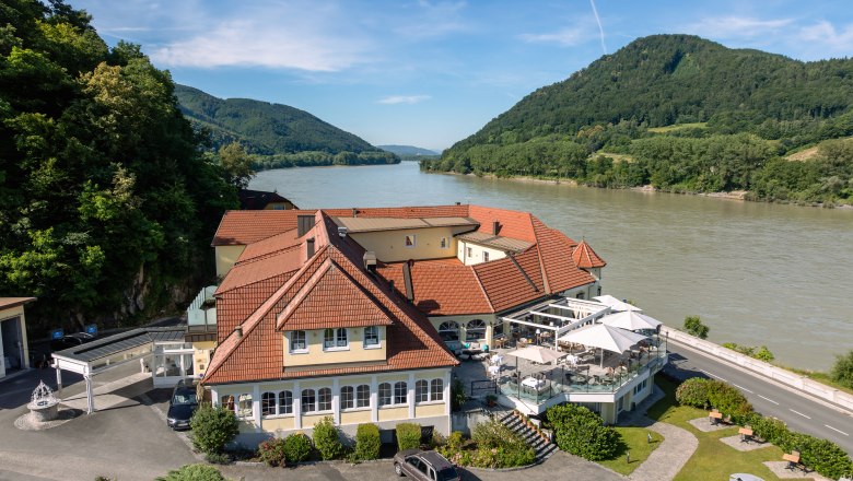 Hotel ResidenzWachau am Flussufer mit umliegenden H&uuml;geln.