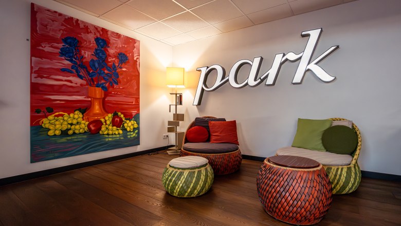Ein stilvoller Hotel-Loungebereich mit bunten Möbeln und einem großen Gemälde an der Wand.