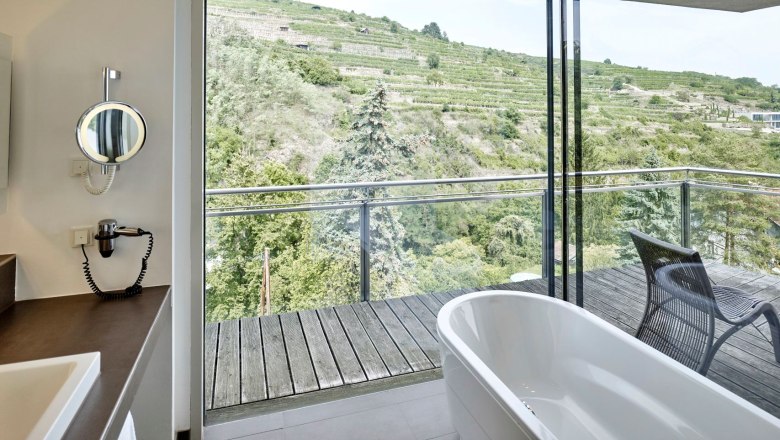 Badezimmer mit freistehender Badewanne und Blick auf Weinberge.