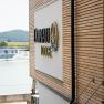 Geb&auml;ude mit Holzverkleidung und Schriftzug 'Donau Lodge', im Hintergrund die Donau und ein Schiff.