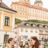 Zwei Frauen genie&szlig;en Eisbecher im Gastgarten mit Blick auf das Stift Melk.